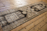 Distressed end of the vintage Oushak runner, with black hook and latch motifs and ivory wear.