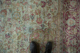Overhead detail of distressed Mahal carpet's worn texture, seafoam green, raspberry, and blue floral pattern.