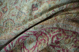 Close-up of distressed Mahal carpet folds, showing pale seafoam, raspberry vinery, and worn texture.