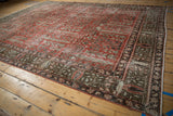 Distressed cinnabar red field of a vintage Persian Khoy carpet, revealing garden of paradise motifs.