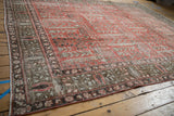 Distressed Khoy rug corner with faded cinnabar red and chocolate brown garden motifs.