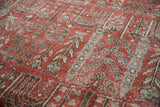 Faded cinnabar red and silver botanical motifs with wear on a distressed Khoy rug.