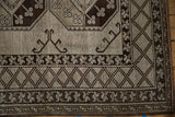 Distressed vintage Ersari rug corner with checkered border, stylized florals, and hook motifs.