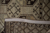 Distressed brown and beige Ersari rug showing geometric guls and checkered border.