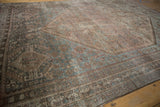 Vintage distressed Kamseh rug's worn geometric patterns in dusty blue and warm brown tones.