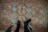 Distressed Belouch rug section showcasing geometric guls and faded raspberry, brown, powder blue.