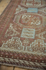 Distressed pile of the vintage Belouch rug, with faded raspberry, chestnut, and blue geometric motifs.