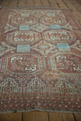 Angled view of distressed Belouch rug, geometric guls, serpent motifs, with faded raspberry and wear.