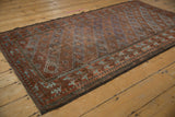 Distressed vintage Belouch rug showing geometric panels in muted chestnut, indigo, and terracotta.