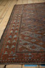 Distressed Belouch rug showing geometric patterns and worn texture in terracotta and blues.