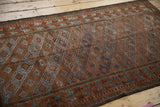 Distressed Belouch rug's diagonal panels with floral geometric motifs in terracotta and powder blue.