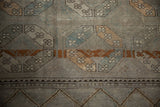 Distressed Ersari runner detail with faded guls in dusty copper, slate blue, and chevron border.