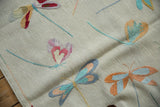 Close-up of the plain woven Pakistani Kilim featuring multi-colored embroidered dragonfly motifs.