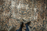 Distressed vintage Bakhtiari rug with scrolling beige, indigo blue, and coffee brown floral patterns.