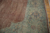 Close-up of distressed copper field meeting dusty sage green Mahal border with floral motifs.