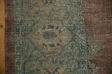 Distressed Mahal carpet's worn pile, revealing dusty sage green field and wide copper border.