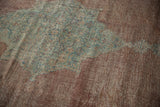 Distressed Mahal rug detail: worn floral finial in dusty blue, sage on a copper field.