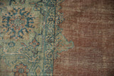 Distressed Mahal carpet's sage green and blue floral border, worn copper field.