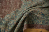 Distressed vintage Mahal carpet corner, featuring worn textures and a wide chestnut border.