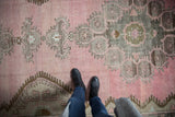 Low pile and worn-in texture of a vintage Kars runner in blush pink and silver-grey tones.