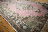 Angled view of the distressed Kars runner's scalloped medallion, abrashed pink field, and detailed border.