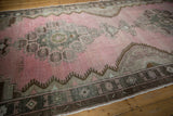 Weaver's signature woven in brown and silver detail on the distressed blush pink field of a Kars runner.
