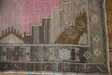 Scalloped medallion contour and geometric border of a vintage Kars rug in pink, silver, and brown.