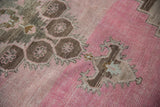 Softly worn texture of a vintage Kars runner's medallion in chocolate brown and bubblegum pink.