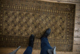 Distressed vintage Afghani rug, geometric floral guls with inverted coloration in gold, brown, and navy.