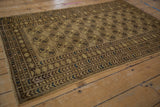 Angled detail of a distressed Afghani rug border, showcasing floral motifs, coffee brown, and dusty gold.