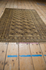 Angled view of vintage distressed Afghani rug's geometric guls in dusty gold and coffee brown.