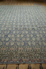 Distressed vintage Sivas rug's ornate ivory border and faded blue field with boteh motifs.