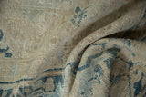 Folded pile of distressed Gorevan carpet with worn texture and faded blue patterns.
