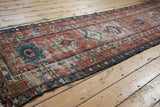 Antique Karaja runner detail with geometric pawn motifs, colorful vinery border, and pile wear.