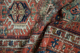 Folded antique Karaja rug detail with geometric patterns and colorful checkered border.