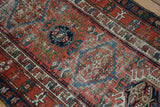 Detail of antique Karaja runner's brick red field, geometric motifs, and vivid checkered vinery border.