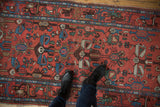 Close detail of vintage Borchalou rug with brick red field, unique stylized animals, and blue border.