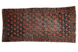 Antique Karabagh rug with repeating red rose lattice, charcoal ground, and geometric border.
