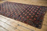 Antique Karabagh rug detail: repeating rose motif, serrated leaf border, and worn pile.