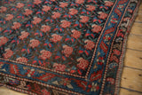 Antique Karabagh rug detail: charcoal brown field with repeating rose motif, indigo blue geometric floral border.