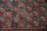 Antique Karabagh rug detail: lattice of madder red roses, indigo leaves, and worn pile texture.