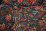 Hand-knotted Karabagh rug detail: madder red roses, indigo blue border, visible foundation.