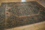 Distressed Shiraz carpet corner, showing geometric borders and chevron patterns in dusty green.
