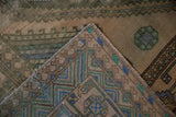 Dusty sandalwood Shiraz carpet corner showing geometric blue, green patterns, and selvage.