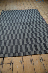 Close-up of hand-woven Pakistani Kilim rug texture, featuring silver and charcoal rectangles with abrashes.