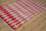 Angled view of a vintage Moroccan rug, highlighting the plush texture and raspberry color abrashes.