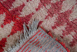 Close-up of the hand-woven back, fringe, and raspberry pile on a vintage Moroccan rug.