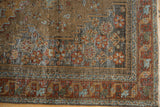 Distressed Malayer rug corner shows worn floral and serpent patterns; madder rust, blue, sandalwood.
