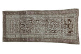 Distressed vintage Caucasian runner rug showing faded geometric plant patterns in charcoal, silver, and mauve.
