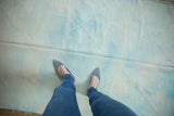 Person's feet on flatweave vintage Turkish Kilim rug, with powder blue and ivory diamond pattern.